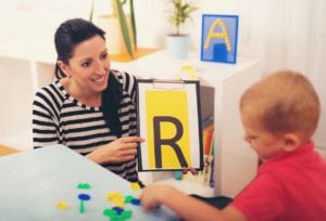 A woman showing a boy how to spell the letter r.